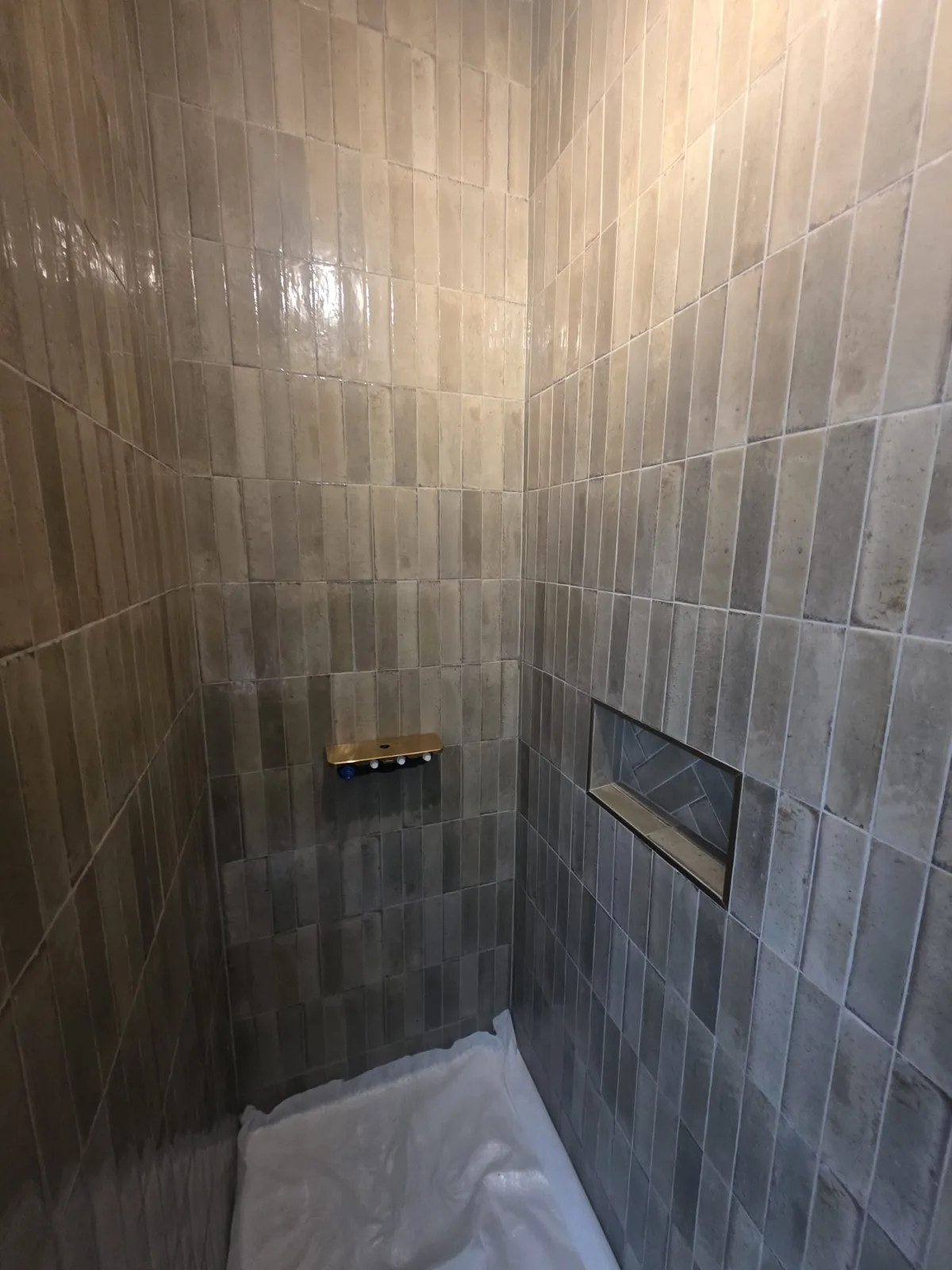Douche carrelée en zellige avec niche décorative et robinetterie laiton