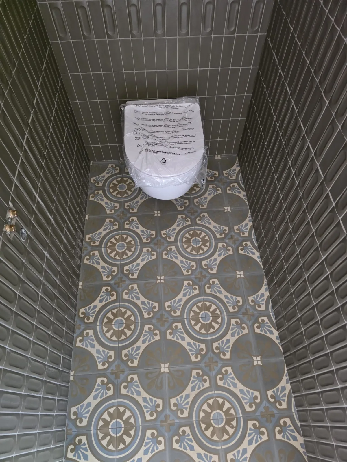 Carrelage relief et sol en carreaux de ciment dans un WC suspendu